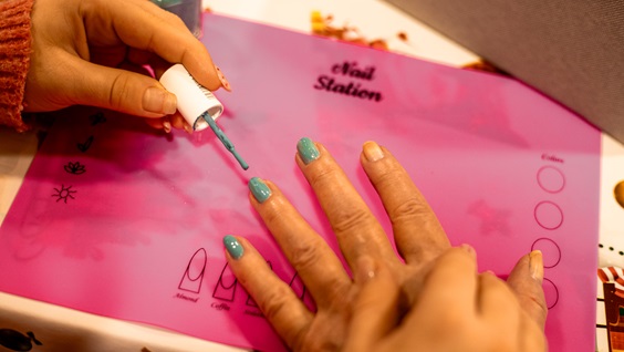 Neglelak og nærvær! Emma giver blågrønne negle, mens snakken går om valgfaget og det at gøre en forskel. Små øjeblikke – stor betydning.